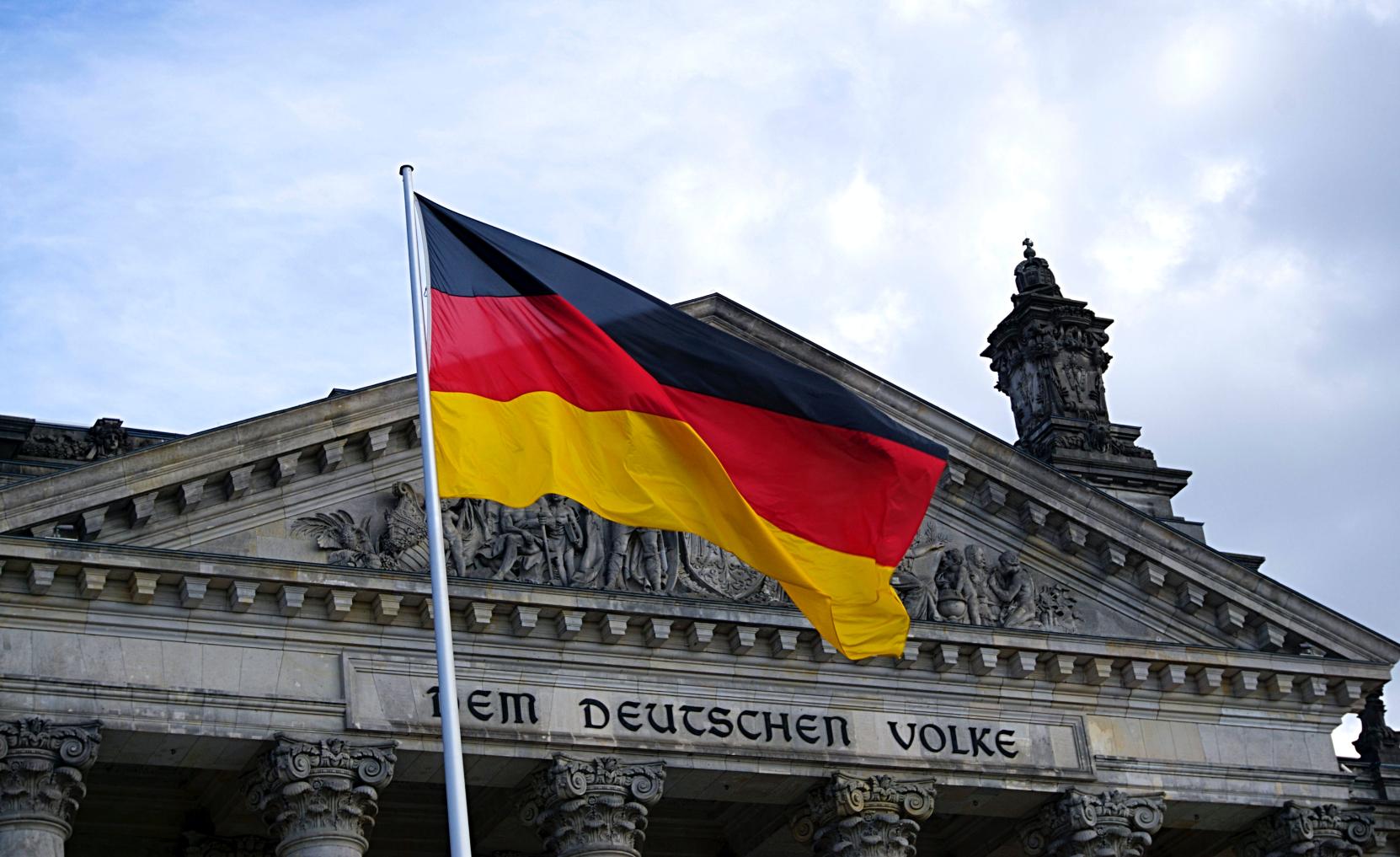 The German flag on a flag pole in front of a historic building.
