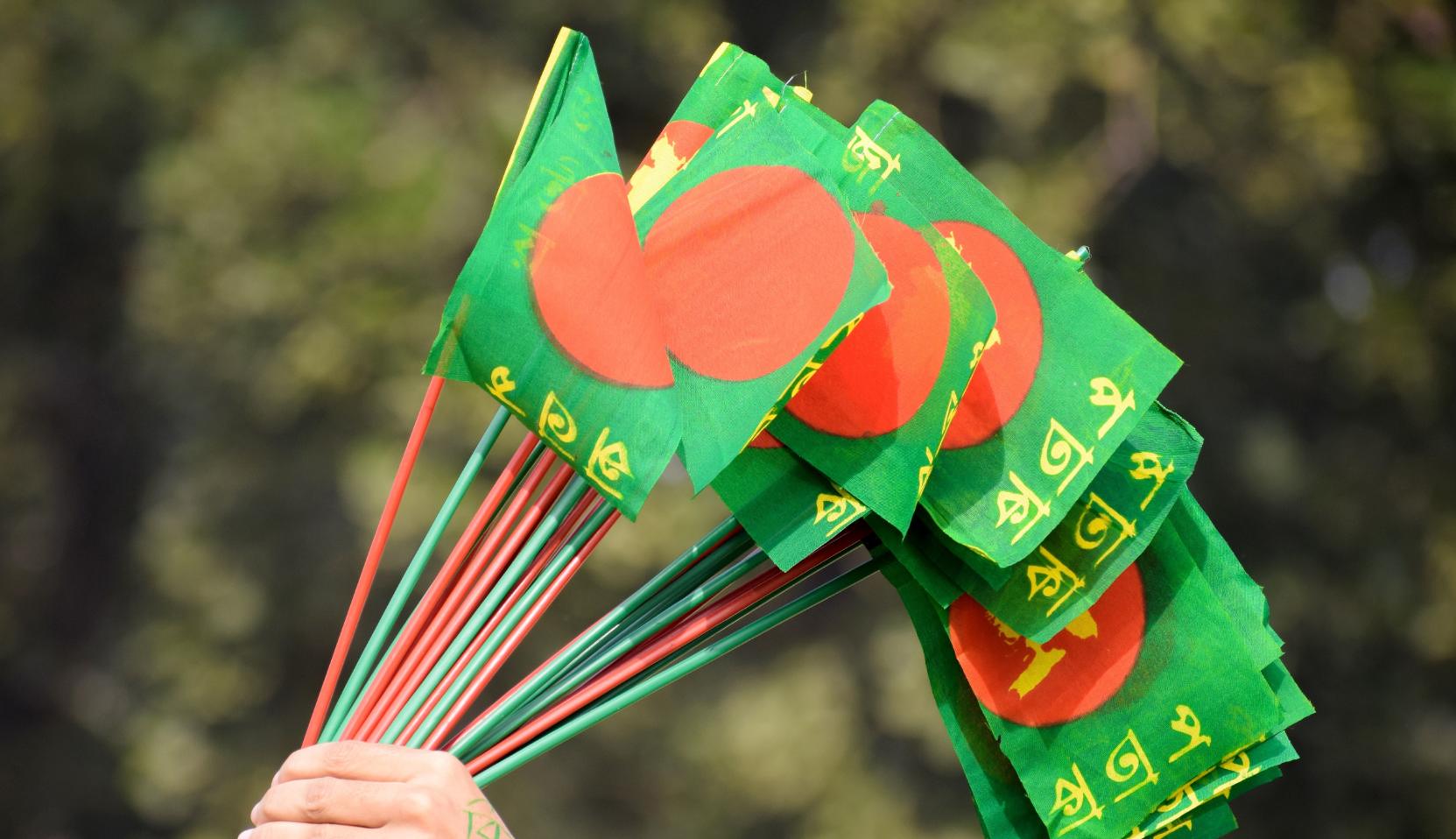 The Bangladesh flag on hand-held sticks.