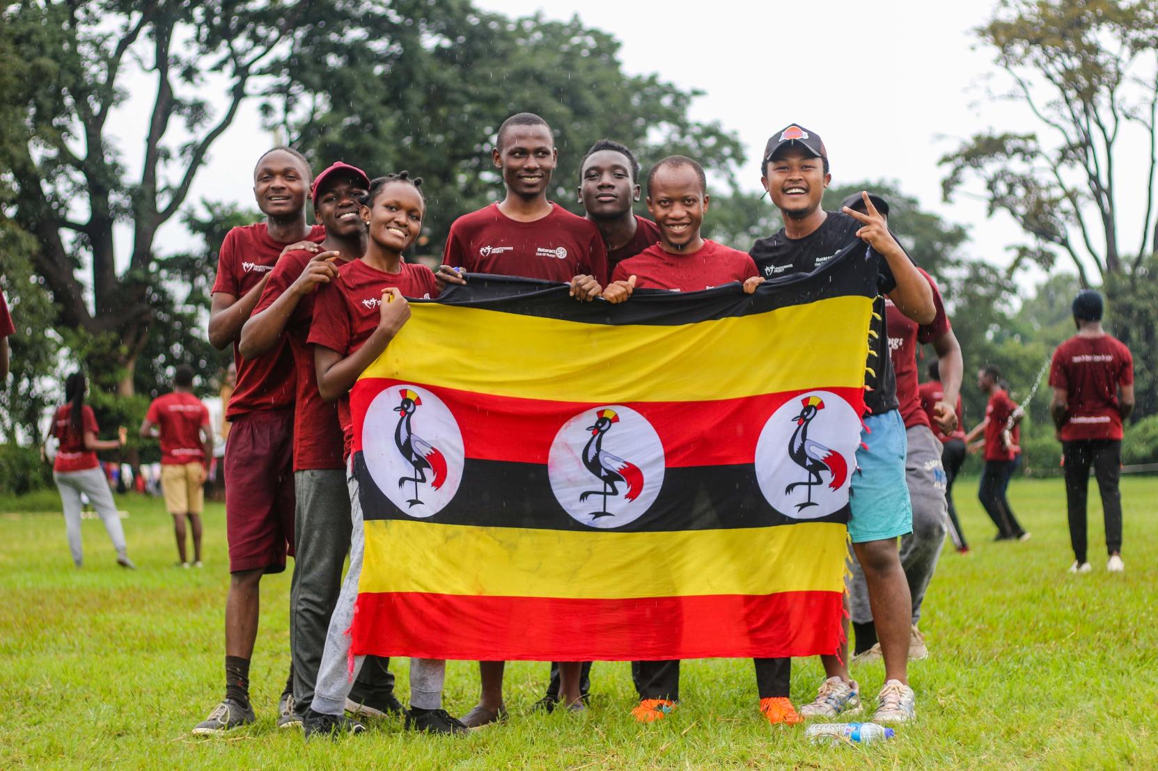 Group of people holding a flag of Uganda.