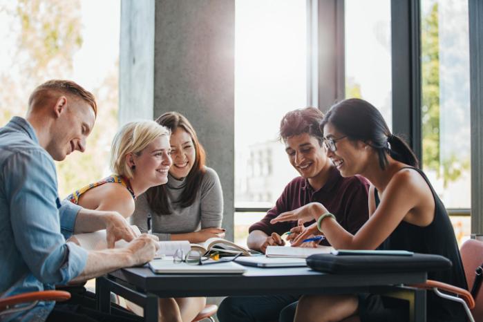 A diverse group of students talk at a table.